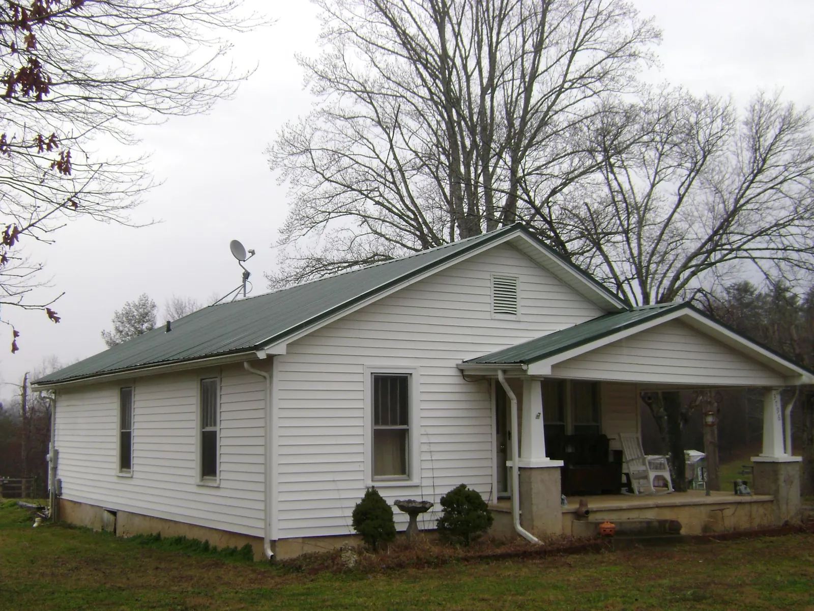 Green metal roof on a white bungalow with a side porch in Rapid City