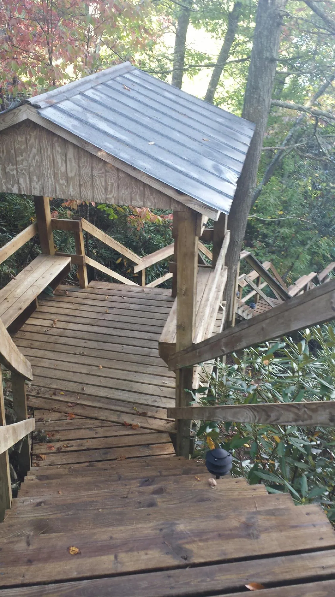 Metal roofed shelter over wooden steps on a wooded walkway — Skylight Repair & Installation work by our crew in Rapid City