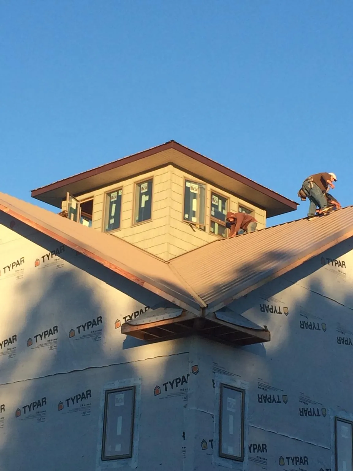 Roofers working around a rooftop cupola on a new metal roof at sunset — Roof Waterproofing in Rapid City by Roofing Brothers